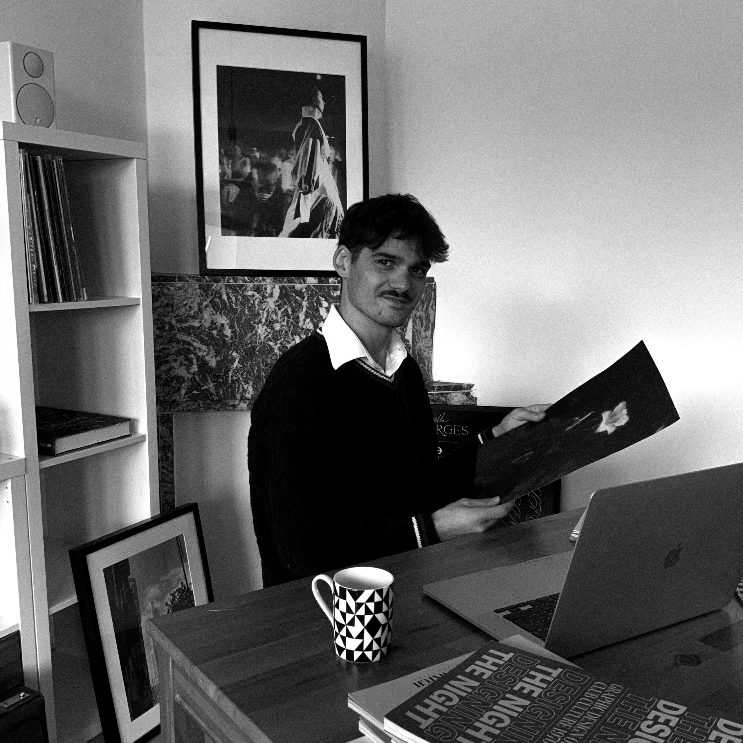 Homme assis à table derrière son macbook regardant une photographie