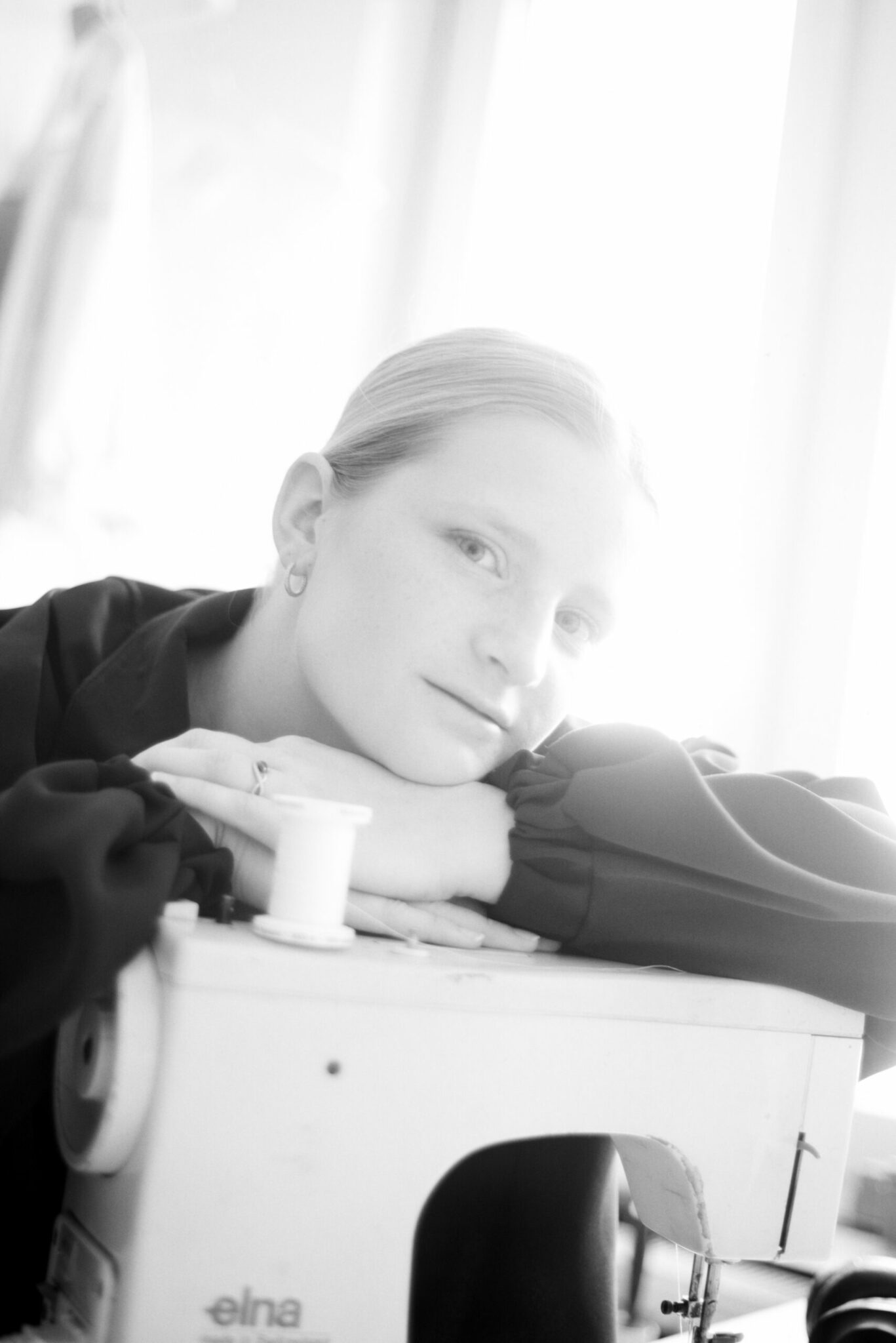 Femme posant sur une machine à coudre en noir et blanc